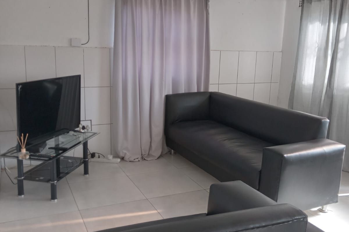 A living room featuring tiled flooring and partial wall tiling, requiring cosmetic updates to improve the overall finish and aesthetic appeal.