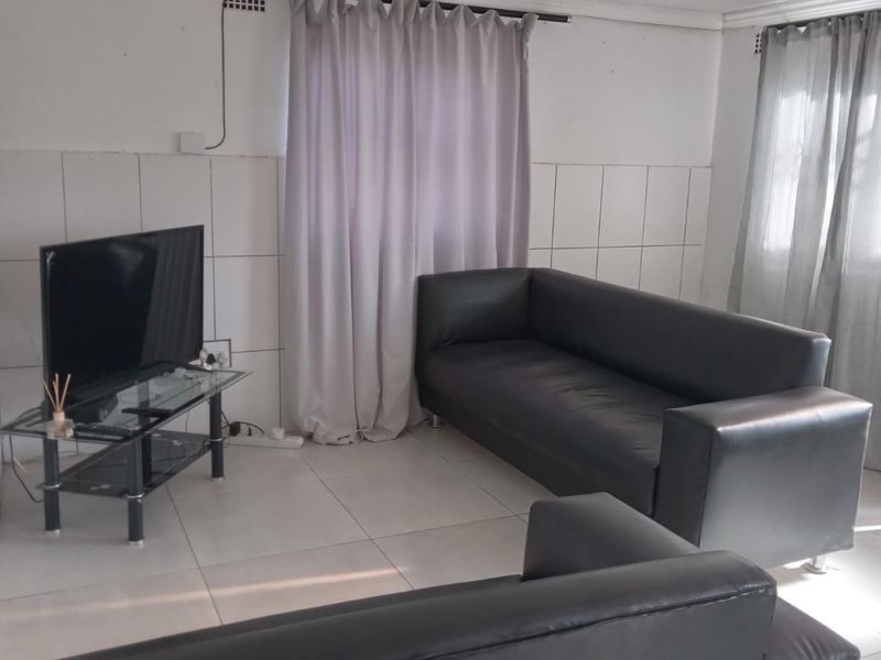 A living room featuring tiled flooring and partial wall tiling, requiring cosmetic updates to improve the overall finish and aesthetic appeal.
