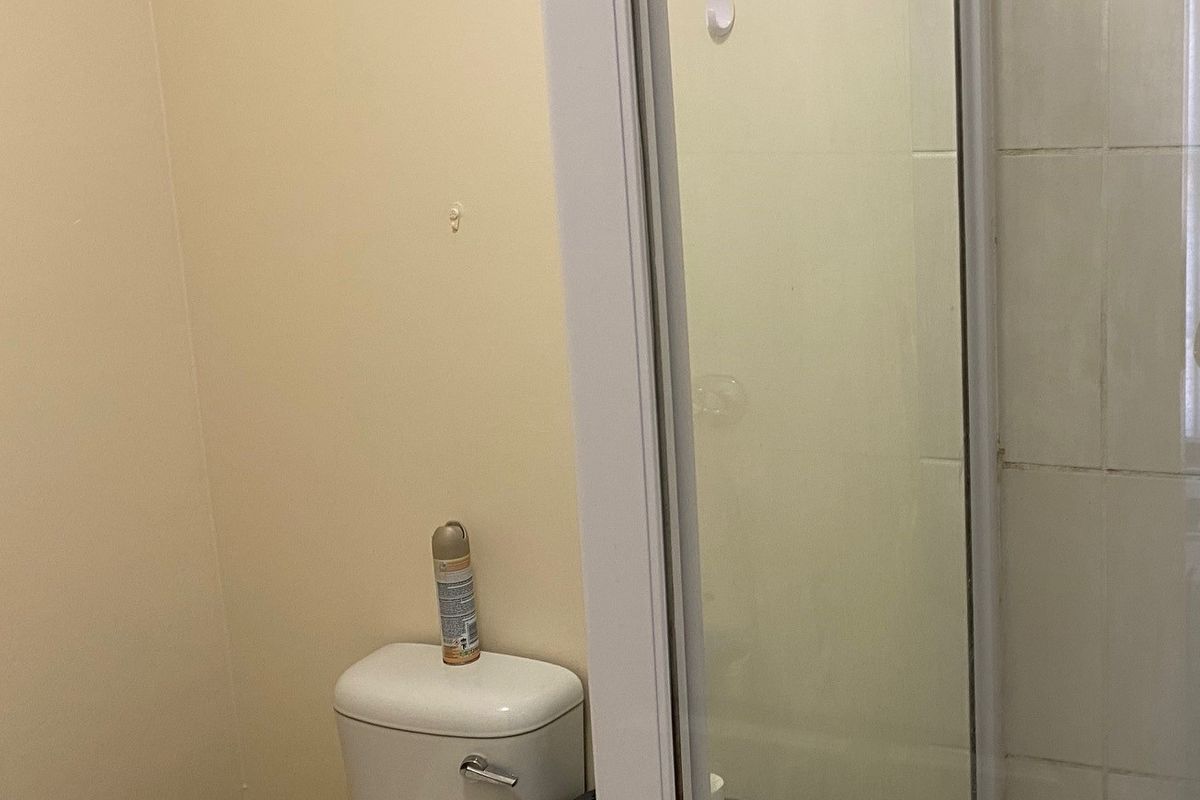 A compact bathroom featuring a standard toilet and a glass-enclosed shower with tiled walls.