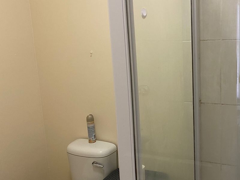 A compact bathroom featuring a standard toilet and a glass-enclosed shower with tiled walls.