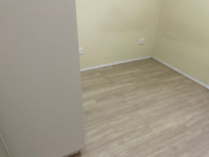 An empty bedroom featuring light-toned laminate flooring and neutral walls with visible electrical outlets.