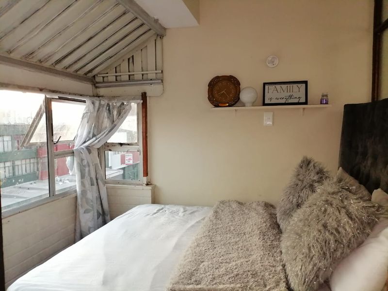 A bedroom featuring a sloped ceiling and casement windows, requiring some cosmetic updates to the window frames and ceiling finishes.