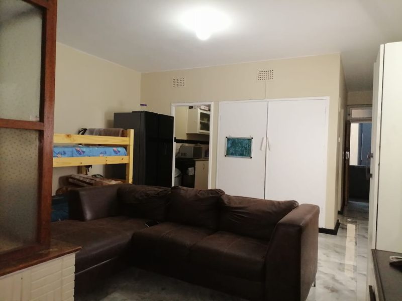 Open plan living area featuring tiled flooring and built-in storage cupboards, with direct access to the kitchen and hallway.