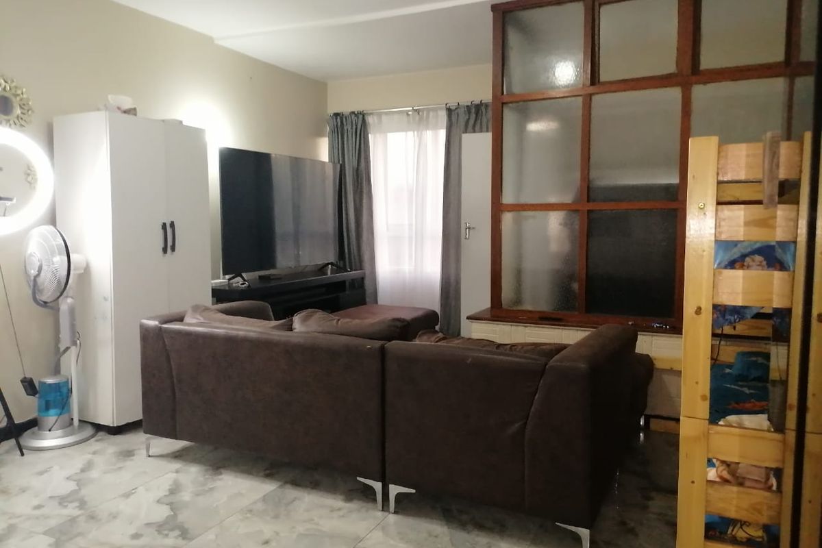 A living room area featuring tiled flooring and a decorative timber-framed glass partition, providing a functional space with natural light from the window.