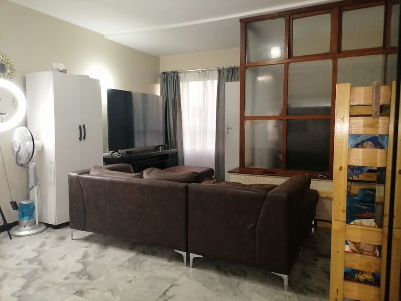 A living room area featuring tiled flooring and a decorative timber-framed glass partition, providing a functional space with natural light from the window.