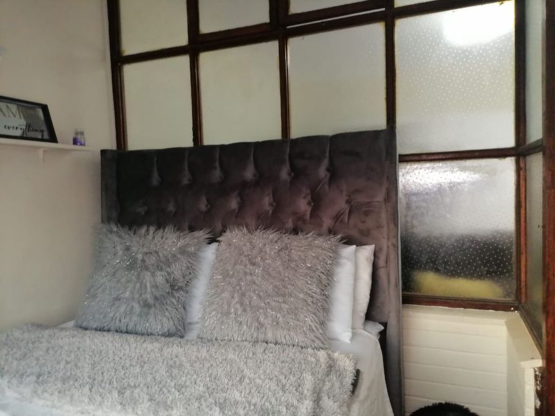 A bedroom featuring a distinctive timber-framed glass partition wall, providing a unique architectural element to the space.