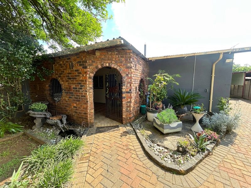 A charming rear courtyard featuring a rustic brick structure with an arched entrance, brick paving, and a small integrated water feature.