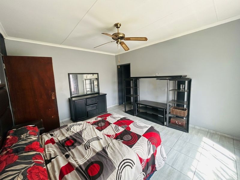 A bedroom featuring tiled flooring and a ceiling fan, providing a functional space with neutral wall tones.