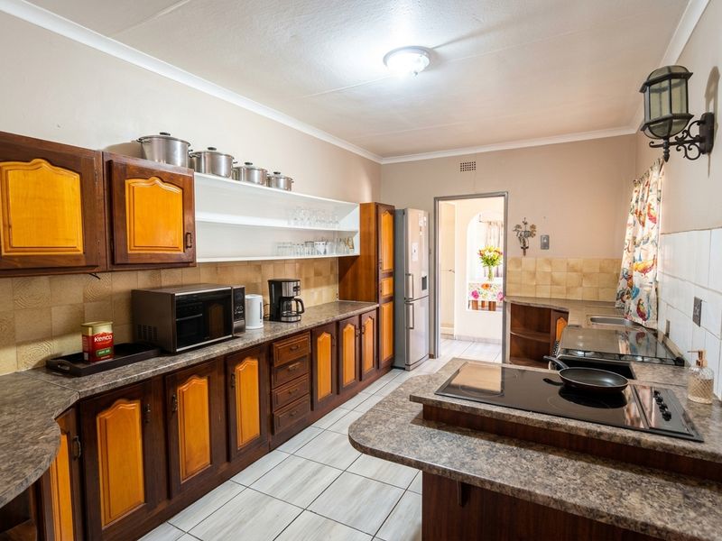 A functional kitchen featuring traditional wooden cabinetry, laminate countertops, ceramic tile flooring, and integrated cooking appliances, offering a classic layout with ample storage space.
