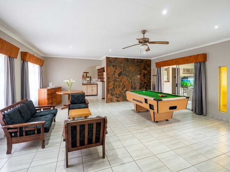 Spacious living area featuring a stone accent wall, tiled flooring, recessed lighting, and a ceiling fan, with direct access to an adjoining space.