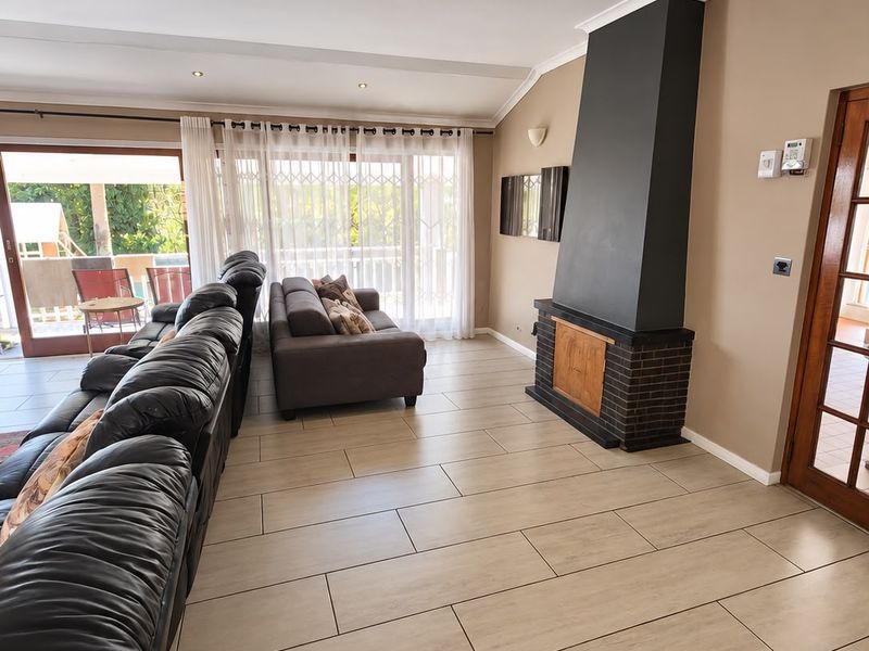Spacious living room featuring modern tiled flooring, a prominent fireplace with a dark chimney breast, and large sliding doors providing access to the patio.
