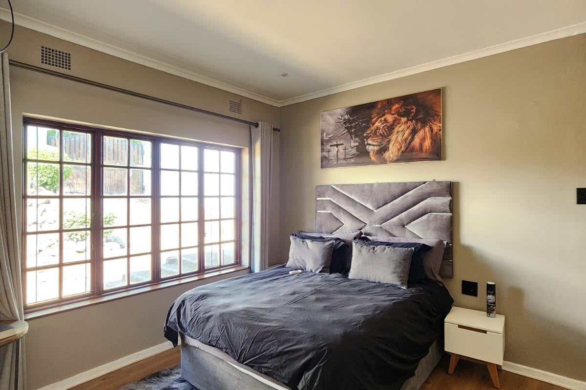 A well-maintained bedroom featuring laminate flooring, large multi-pane windows providing natural light, and recessed ceiling lighting.