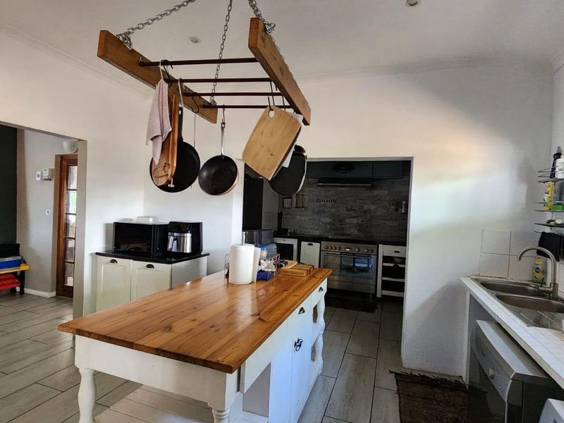 A functional kitchen featuring a central wooden island, double sink, and a separate scullery area with built-in oven and extractor fan.