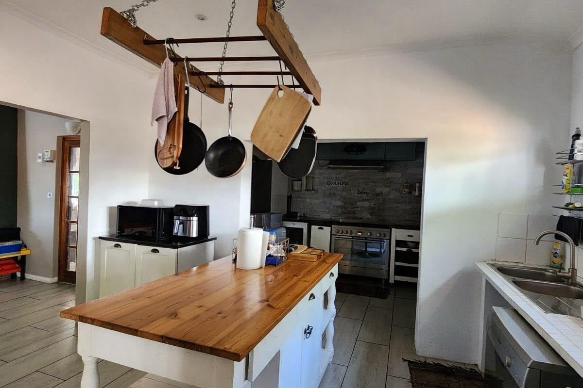 A functional kitchen featuring a central wooden island, double sink, and a separate scullery area with built-in oven and extractor fan.