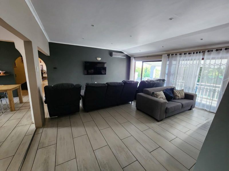 Spacious living room featuring tiled flooring, recessed lighting, an air conditioning unit, and large sliding glass doors providing access to the outdoor area.