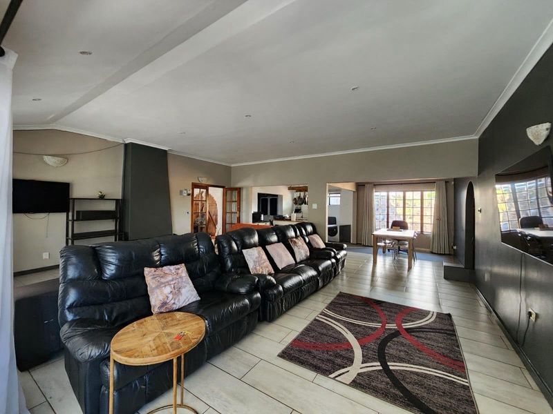 Spacious open-plan living area featuring tiled flooring, recessed lighting, and a central fireplace, offering a versatile layout for lounge and dining arrangements.