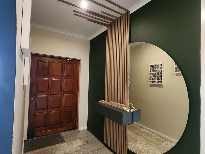 Welcoming entrance hall featuring a stylish timber slat feature wall, built-in floating console, and classic solid timber panelled front door.