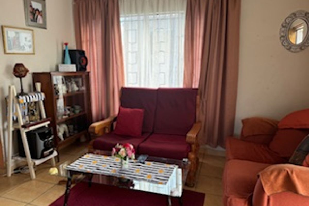 A cozy living room featuring tiled flooring and large windows with curtains, providing a functional and comfortable space for relaxation.