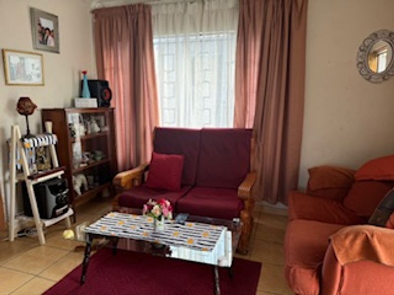 A cozy living room featuring tiled flooring and large windows with curtains, providing a functional and comfortable space for relaxation.