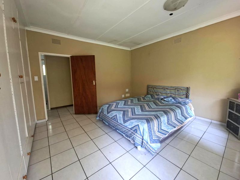 A bedroom featuring tiled flooring and built-in cupboards, showing signs of wear and ceiling water staining, offering potential for cosmetic updates.