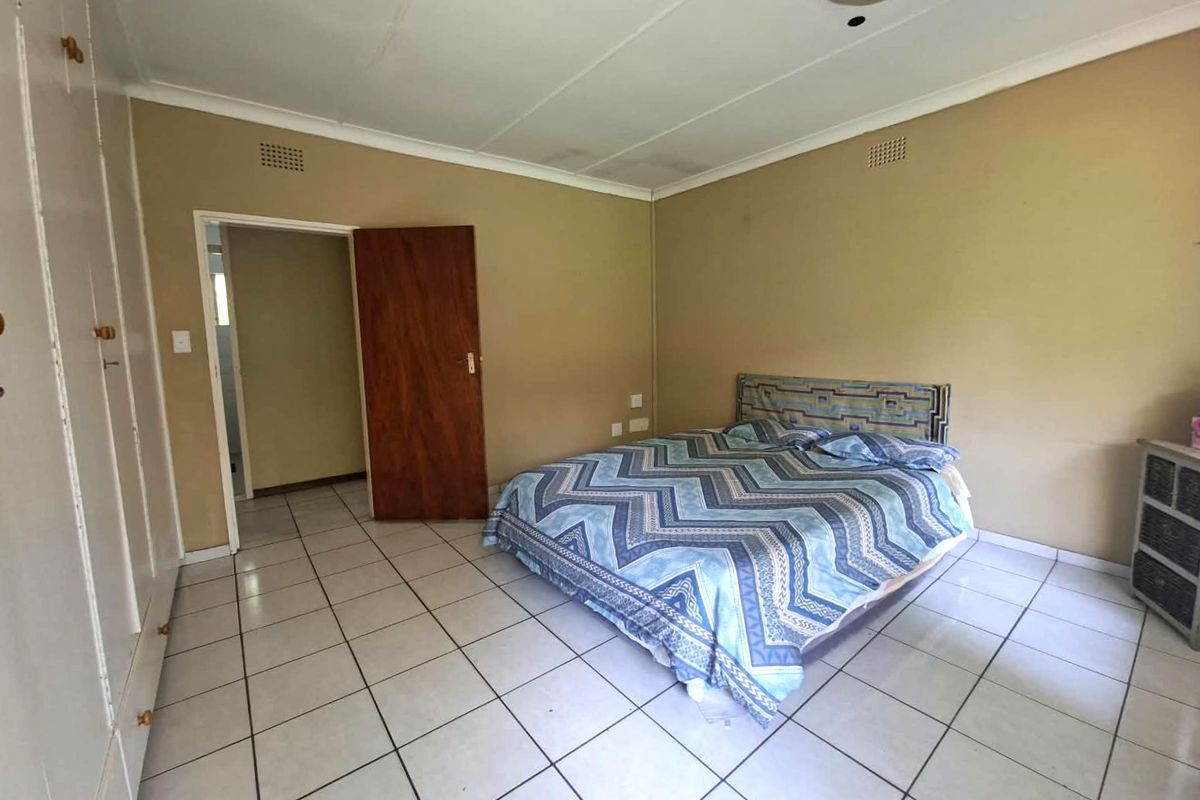 A bedroom featuring tiled flooring and built-in cupboards, showing signs of wear and ceiling water staining, offering potential for cosmetic updates.