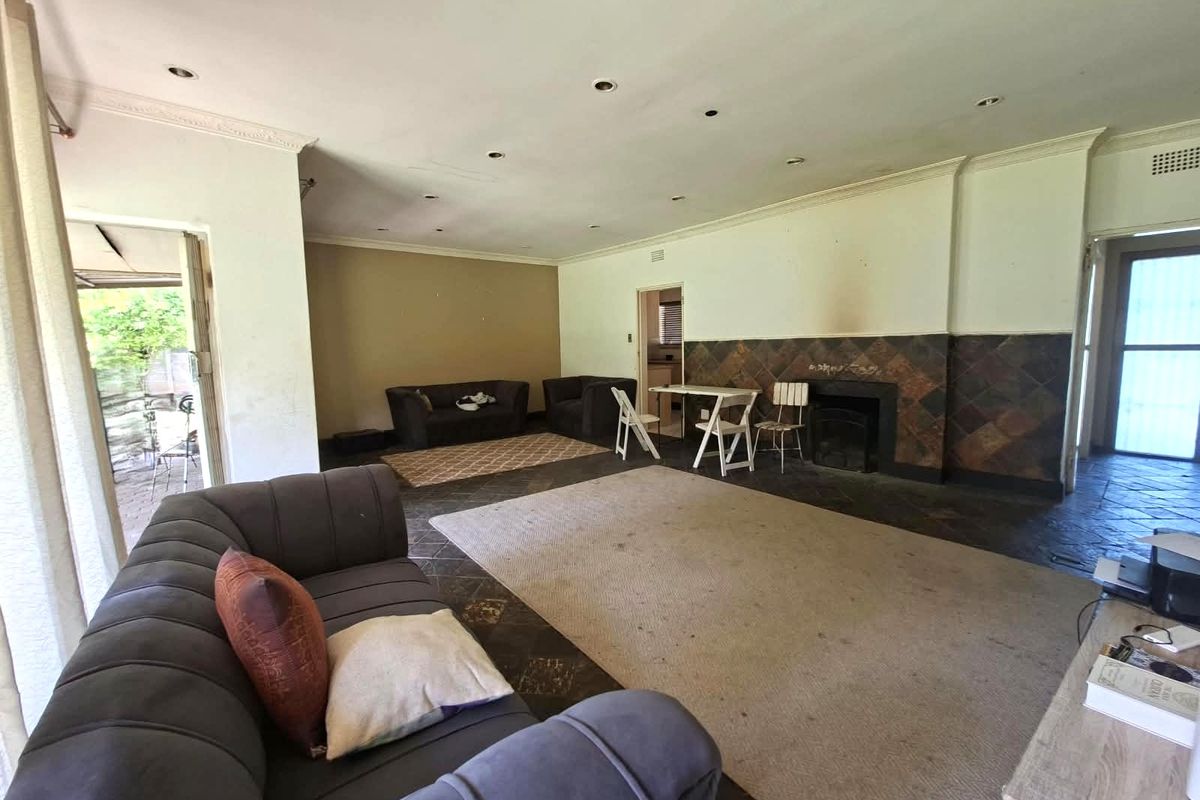 Spacious living room featuring slate tile flooring, a built-in fireplace with a tiled surround, and recessed lighting, offering a blank canvas for renovation.
