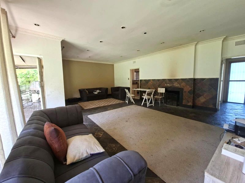 Spacious living room featuring slate tile flooring, a built-in fireplace with a tiled surround, and recessed lighting, offering a blank canvas for renovation.