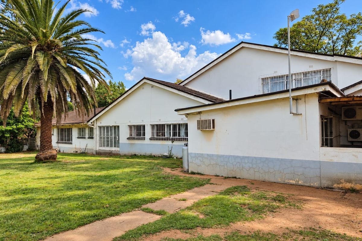 Rear view of the property featuring a large garden, tiled roof, and exterior walls showing signs of wear and weathering.