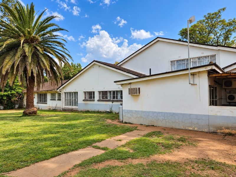 Rear view of the property featuring a large garden, tiled roof, and exterior walls showing signs of wear and weathering.