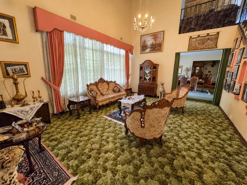 Spacious living room featuring a double-height ceiling, a mezzanine level, and large windows, offering a classic layout with potential for modern updates.