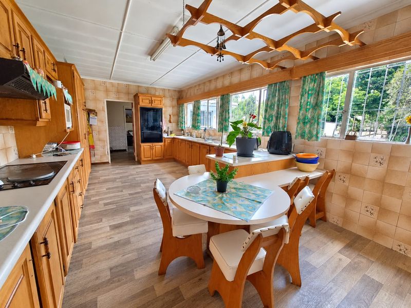 Spacious kitchen featuring extensive wooden cabinetry, built-in oven, hob, and a unique decorative wooden ceiling feature, offering significant potential for modern renovation.
