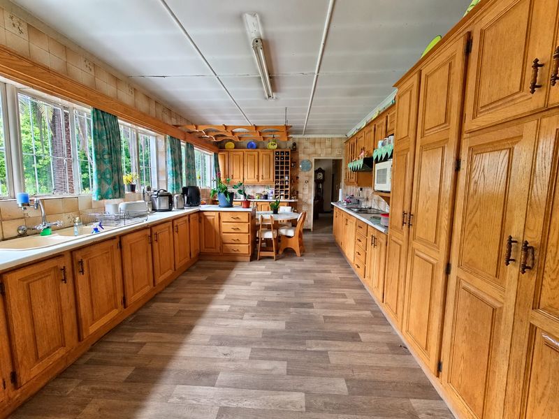 Spacious kitchen featuring extensive wooden cabinetry, laminate flooring, and a functional layout with ample counter space and integrated appliances.