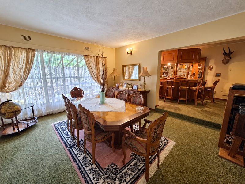 Open plan dining area featuring a raised platform with a built-in bar, large windows, and traditional finishes.