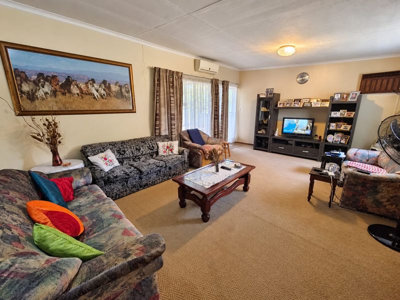 Spacious living room featuring carpeted flooring, a wall-mounted air conditioning unit, and sliding glass doors leading to the exterior.