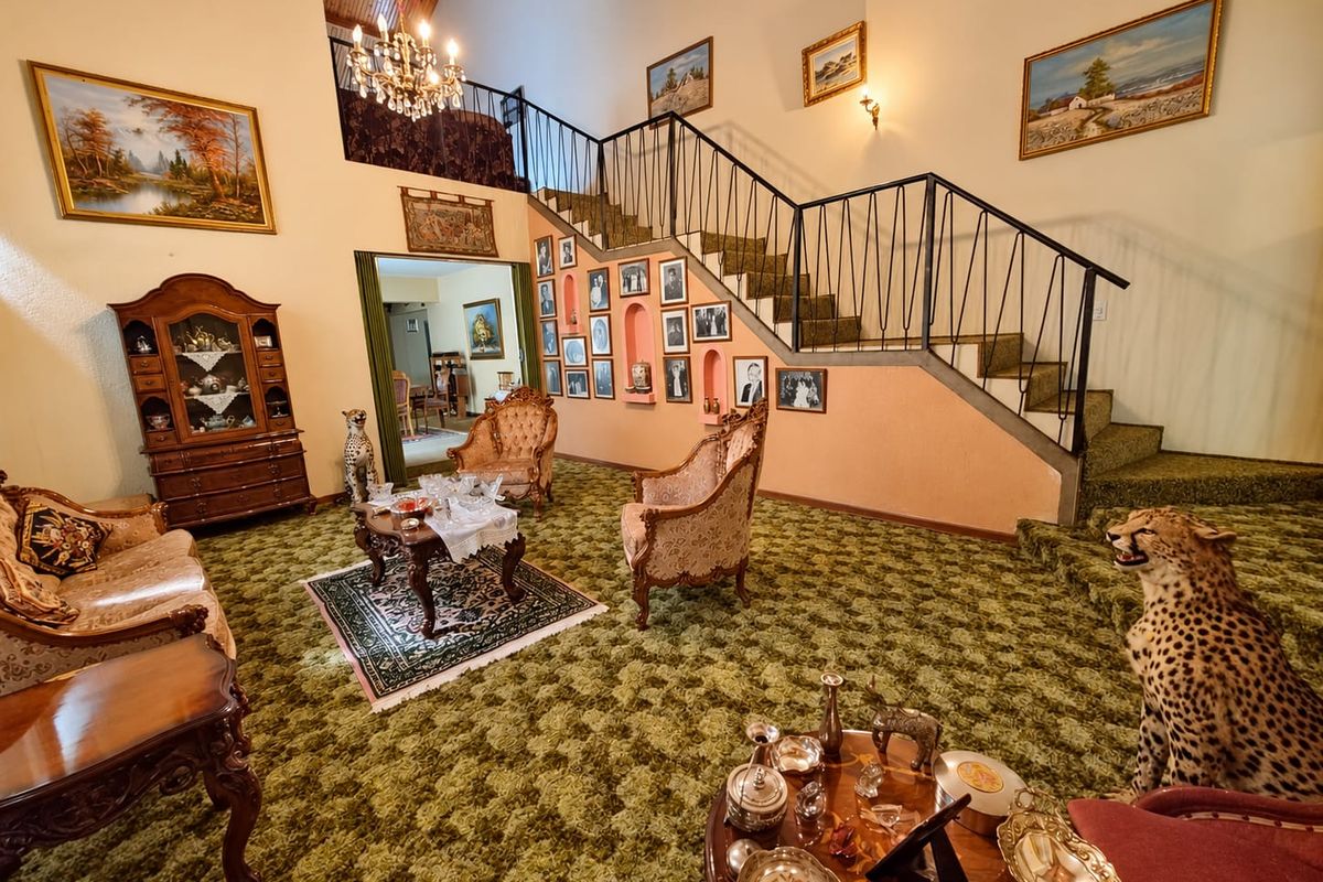 Spacious living room featuring a prominent staircase with wrought iron balustrade, vaulted timber ceilings, and unique recessed wall niches.