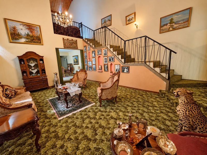 Spacious living room featuring a prominent staircase with wrought iron balustrade, vaulted timber ceilings, and unique recessed wall niches.