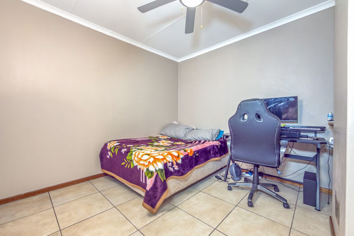 A functional bedroom featuring tiled flooring, a ceiling fan, and neutral wall finishes, providing a versatile space for rest or study.