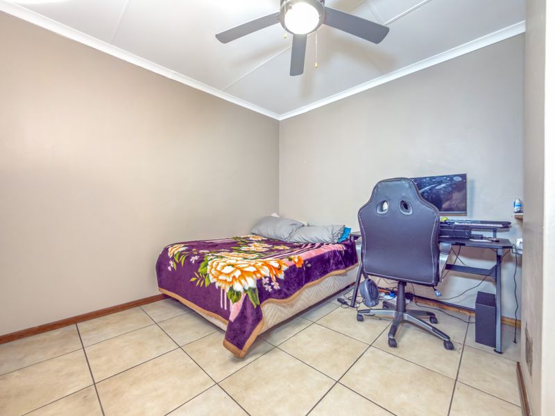 A functional bedroom featuring tiled flooring, a ceiling fan, and neutral wall finishes, providing a versatile space for rest or study.