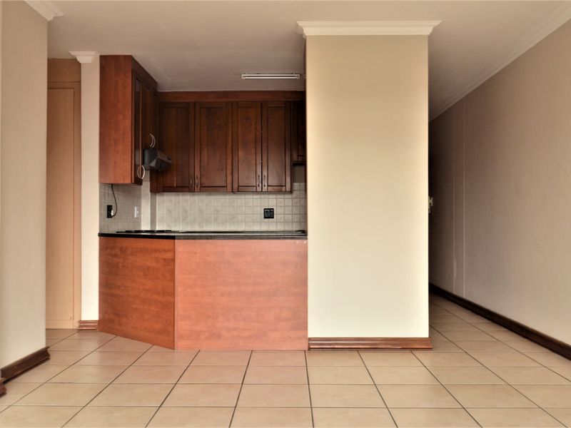 An empty kitchen area featuring dark wood cabinetry, tiled backsplash, and ceramic flooring, offering a functional space ready for personalization.