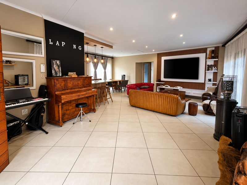 Spacious open-plan living area featuring large format floor tiles, a modern media wall, and a breakfast bar with pendant lighting.