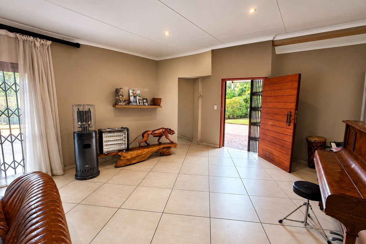 Spacious living area featuring neutral tiled flooring, recessed lighting, and a solid timber entrance door leading to the exterior.