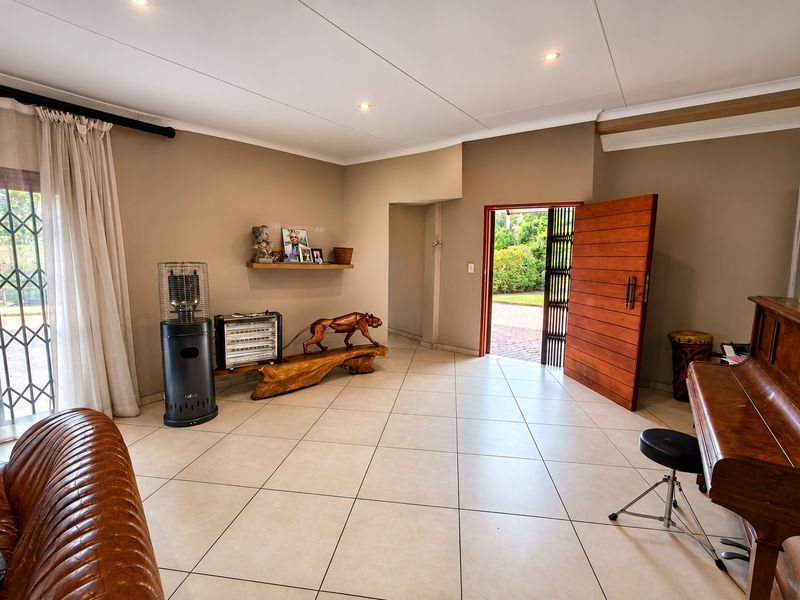 Spacious living area featuring neutral tiled flooring, recessed lighting, and a solid timber entrance door leading to the exterior.