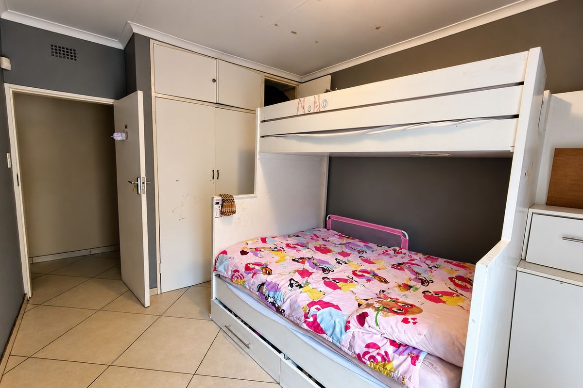 A bedroom featuring tiled flooring and built-in cupboards, requiring some cosmetic updates and ceiling repairs to improve its overall condition.