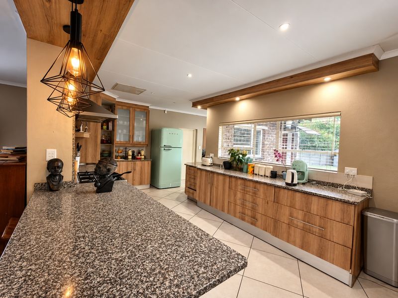 Modern kitchen featuring wood veneer cabinetry, granite countertops, integrated extractor fan, and recessed lighting, offering a functional and stylish workspace.