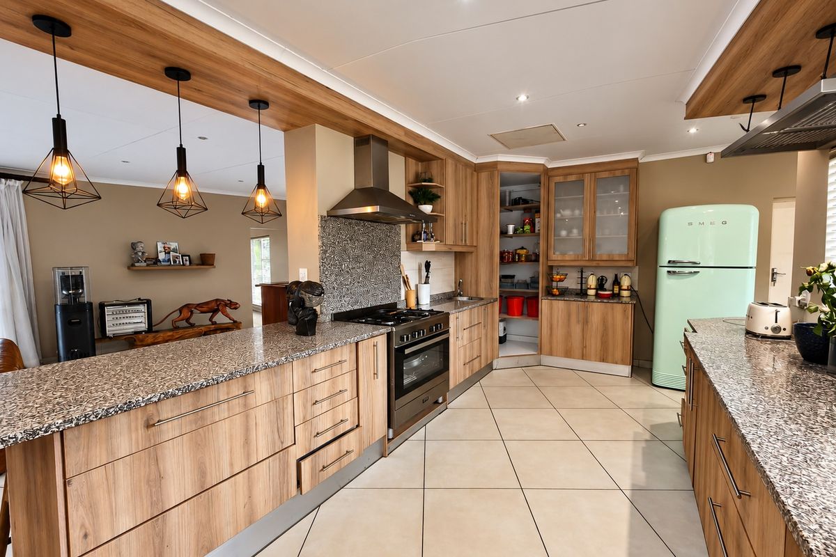 Modern kitchen featuring wood-finish cabinetry, granite countertops, a gas hob with extractor, and a convenient walk-in pantry, finished with neutral floor tiles.