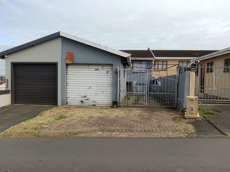 Front exterior view of the property featuring a garage, roller shutter door, metal security gate, and a paved driveway area.