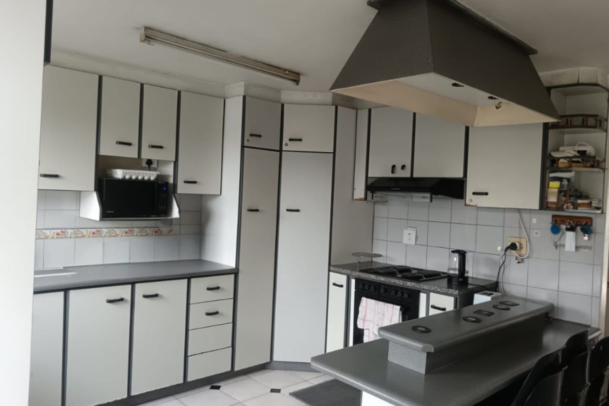 A functional kitchen featuring built-in cabinetry, a gas hob with extractor fan, tiled backsplash, and a breakfast bar area.