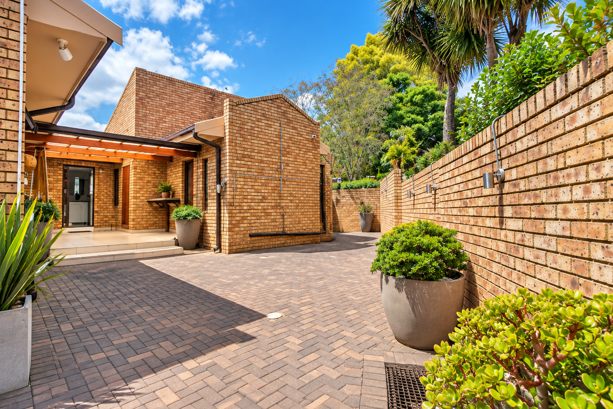 A well-maintained rear courtyard featuring brick construction, paved flooring, and a timber pergola, providing a private and functional outdoor living space.
