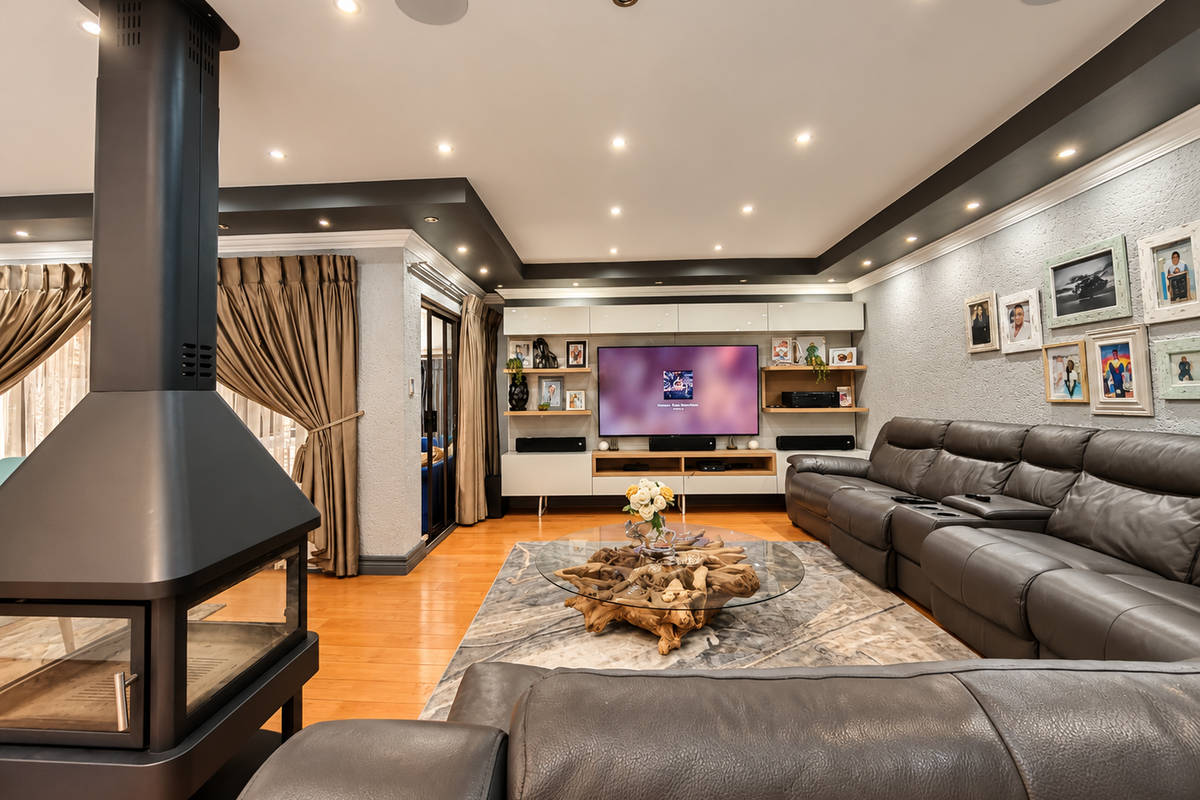 A well-appointed living room featuring a modern freestanding fireplace, hardwood flooring, recessed lighting, and custom built-in media cabinetry.