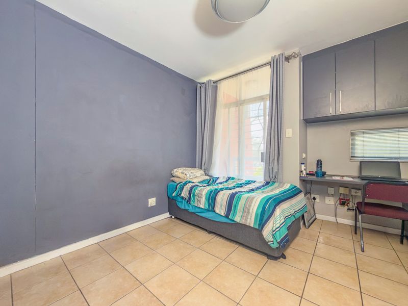 A bedroom featuring tiled flooring, a built-in desk area with overhead cabinetry, and a sliding glass door providing access to the exterior.